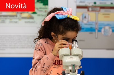 Bambina che guarda dentro un microscopio